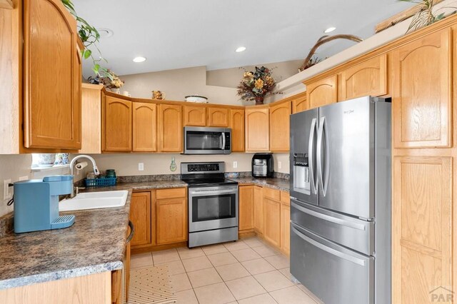 kitchen with light tile patterned floors, vaulted ceiling, stainless steel appliances, a sink, and recessed lighting