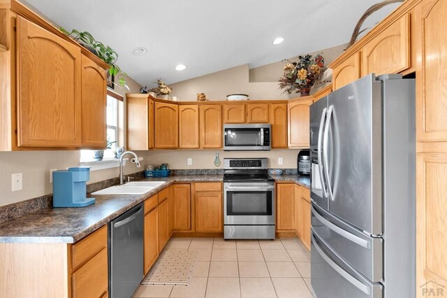 kitchen with dark countertops, stainless steel appliances, a sink, and light tile patterned flooring