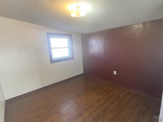 empty room featuring dark wood-type flooring and vaulted ceiling