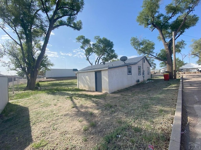 exterior space with a lawn, fence, and stucco siding