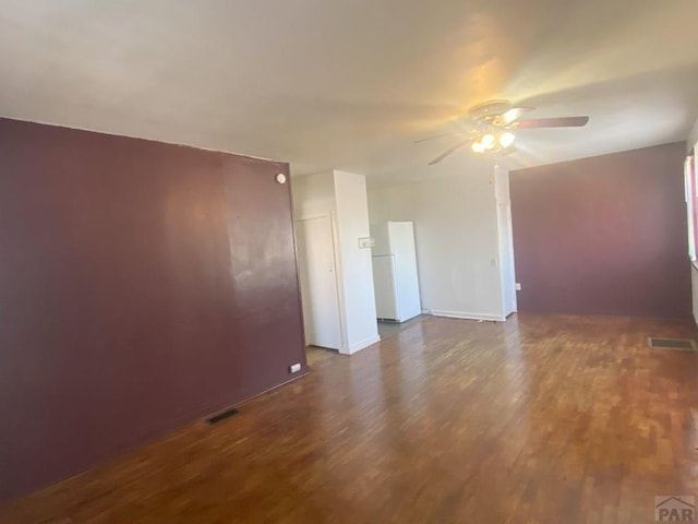 empty room featuring dark wood-style floors, ceiling fan, and visible vents