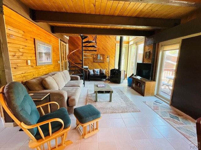 44 Valley Vista Rd Unit 35, Cuchara, CO 81055 - tiled living area featuring stairs, wooden ceiling, beam ceiling, a wood stove, and wood walls