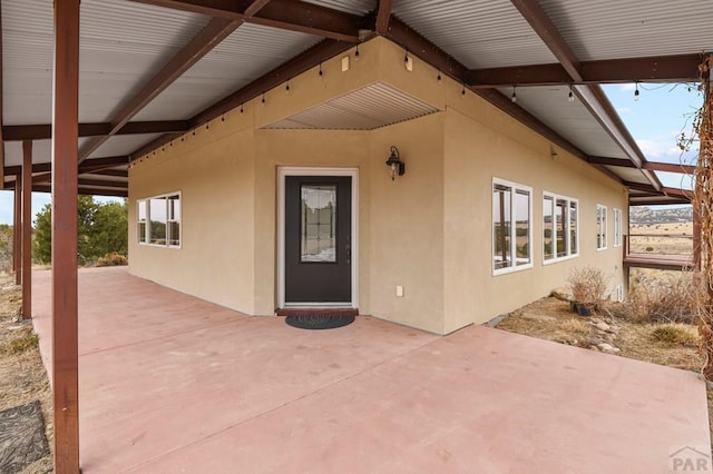 view of exterior entry with a patio area and stucco siding