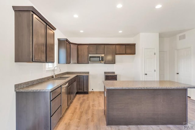 kitchen featuring visible vents, stainless steel appliances, a sink, and a center island