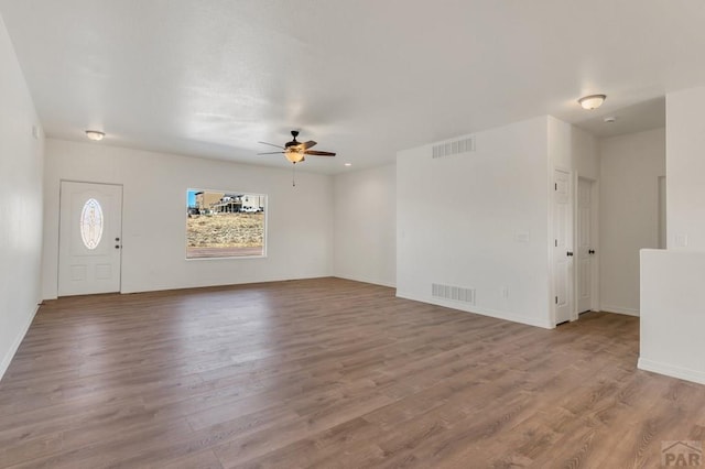 unfurnished living room featuring a ceiling fan, baseboards, visible vents, and wood finished floors