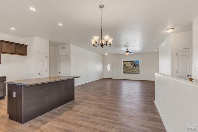 kitchen with light wood finished floors, recessed lighting, hanging light fixtures, open floor plan, and dark brown cabinets