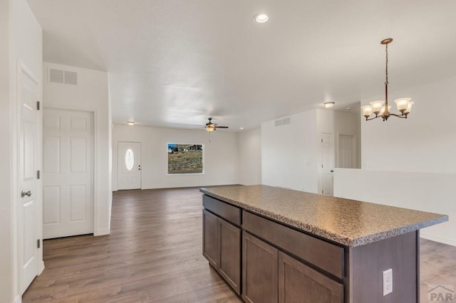 kitchen with open floor plan, a kitchen island, visible vents, and pendant lighting