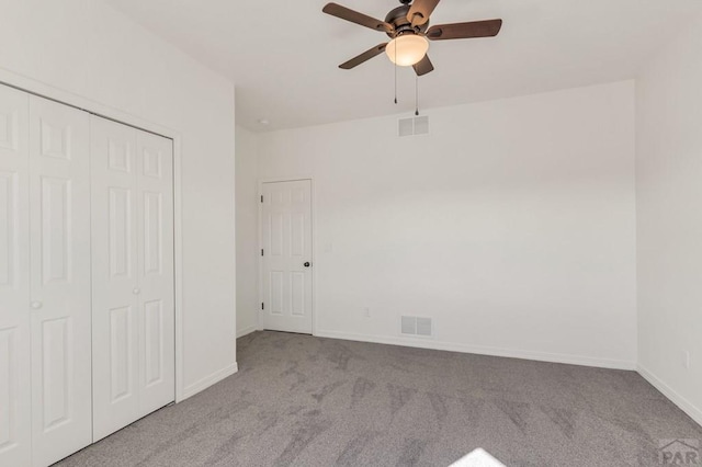 unfurnished bedroom with a closet, visible vents, light carpet, and baseboards