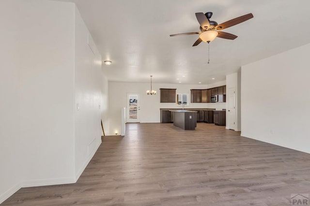 unfurnished living room featuring ceiling fan with notable chandelier, a sink, recessed lighting, and wood finished floors