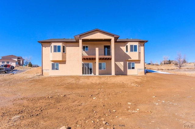 back of house featuring a balcony and stucco siding