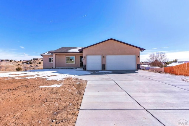 ranch-style home featuring a garage, concrete driveway, fence, and stucco siding