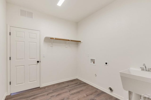 laundry room featuring a sink, laundry area, visible vents, and wood finished floors