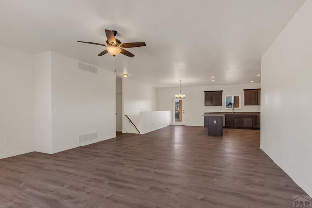 unfurnished living room featuring visible vents, dark wood finished floors, baseboards, and ceiling fan with notable chandelier