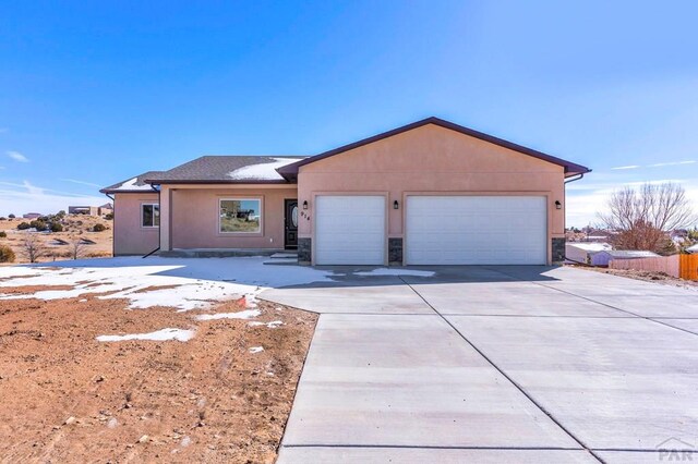 single story home with an attached garage, fence, concrete driveway, stone siding, and stucco siding