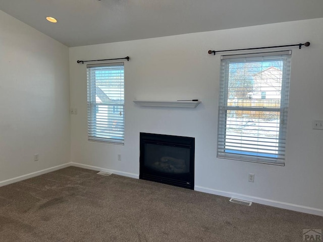 unfurnished living room with recessed lighting, visible vents, baseboards, dark carpet, and a glass covered fireplace