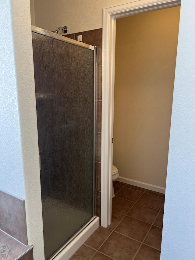 full bath with toilet, a shower stall, baseboards, and tile patterned floors