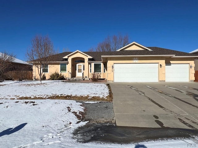 ranch-style home featuring concrete driveway, roof with shingles, an attached garage, and stucco siding