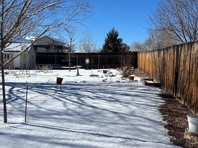 yard layered in snow featuring a fenced backyard