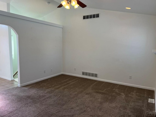 carpeted empty room featuring a ceiling fan, arched walkways, visible vents, and lofted ceiling