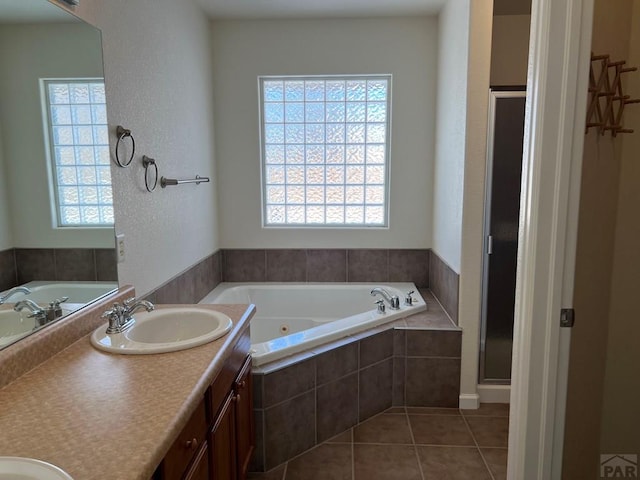 bathroom featuring a whirlpool tub, tile patterned flooring, a sink, and plenty of natural light