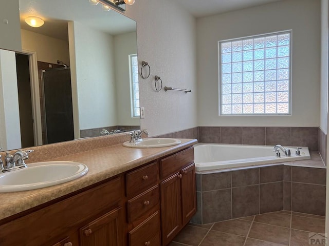 full bathroom with a garden tub, double vanity, a sink, and tile patterned floors