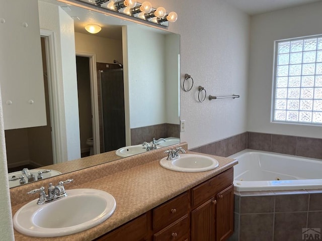 bathroom featuring double vanity, a tub with jets, and a sink