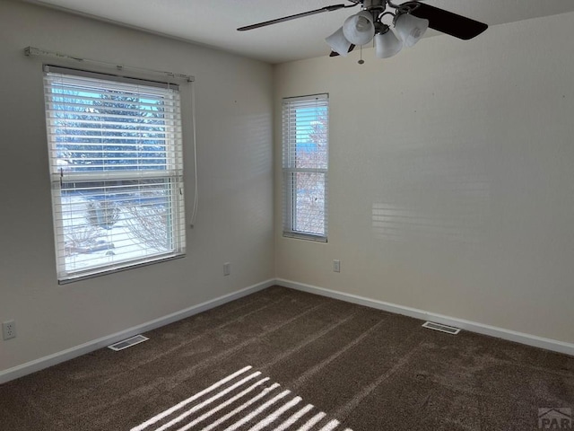 unfurnished room with baseboards, visible vents, and dark carpet