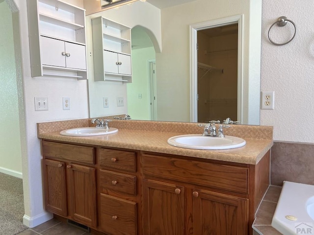 full bathroom with a walk in closet, visible vents, a sink, and double vanity