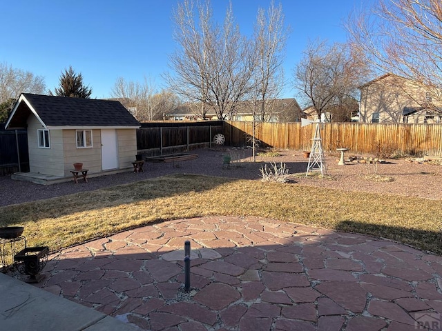 view of yard featuring an outbuilding, a patio area, and a fenced backyard