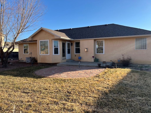 rear view of property featuring stucco siding, roof with shingles, a yard, and a patio