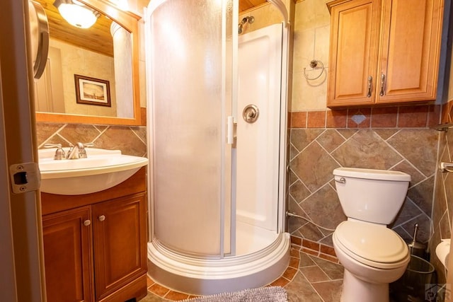 bathroom featuring tile patterned flooring, toilet, vanity, tile walls, and a shower stall