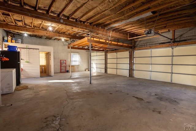 garage with a garage door opener and freestanding refrigerator