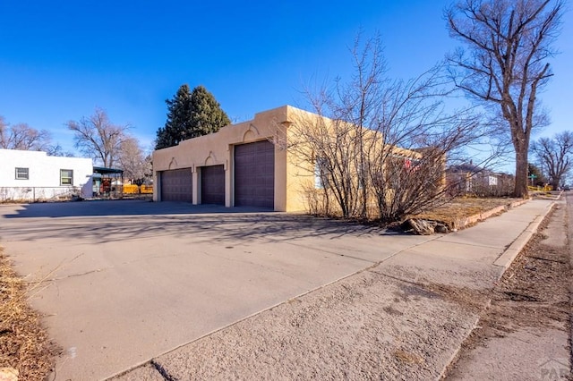 view of property exterior featuring a garage, driveway, and stucco siding