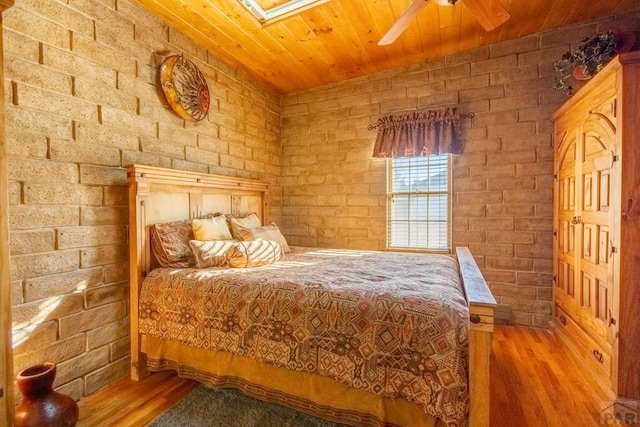 bedroom featuring wooden ceiling, brick wall, and wood finished floors