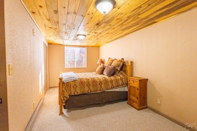 bedroom featuring light carpet, wood ceiling, and baseboards