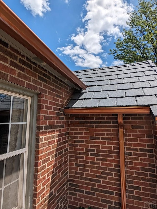 view of side of home featuring a shingled roof and brick siding