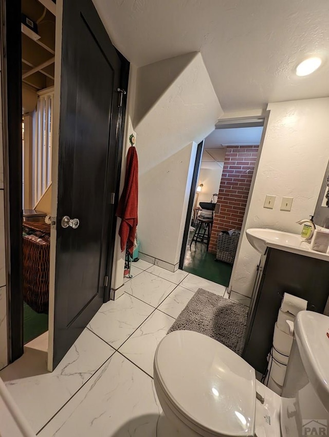 bathroom featuring marble finish floor, vanity, toilet, and a textured ceiling