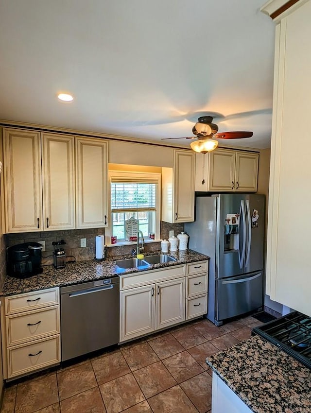 kitchen with appliances with stainless steel finishes, dark stone countertops, a sink, and decorative backsplash