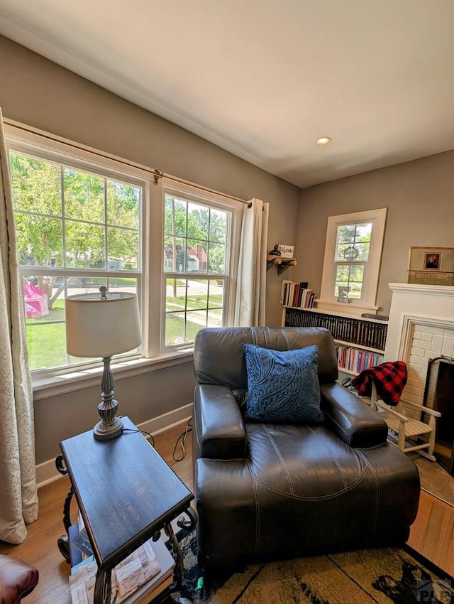 living room featuring recessed lighting, a brick fireplace, wood finished floors, and baseboards