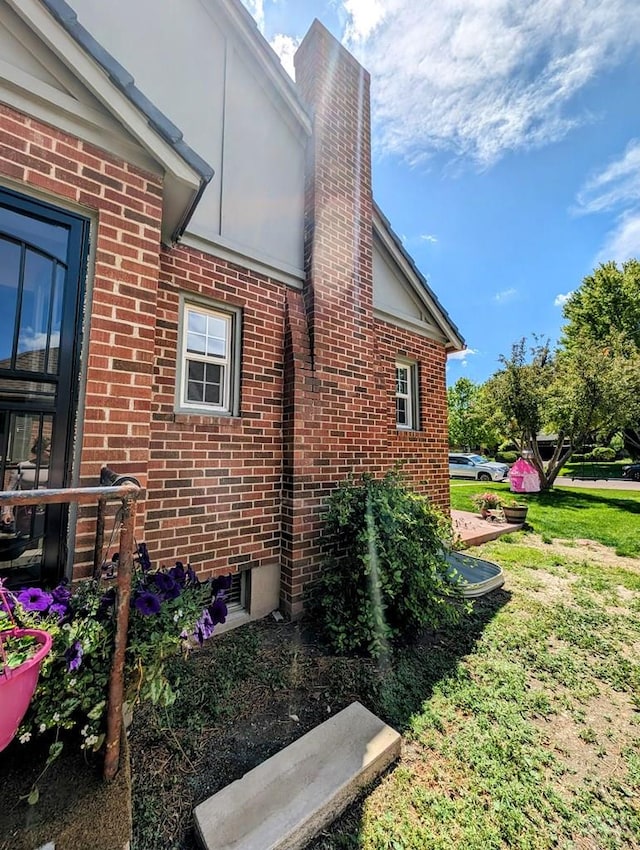 view of property exterior with a yard, brick siding, and a chimney