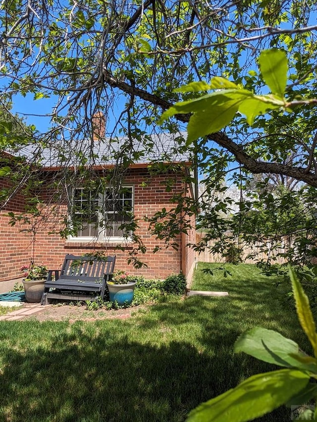 view of side of home featuring brick siding, a lawn, and a chimney