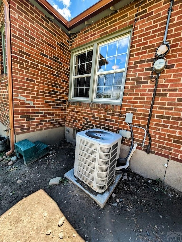 details with central air condition unit, electric meter, and brick siding