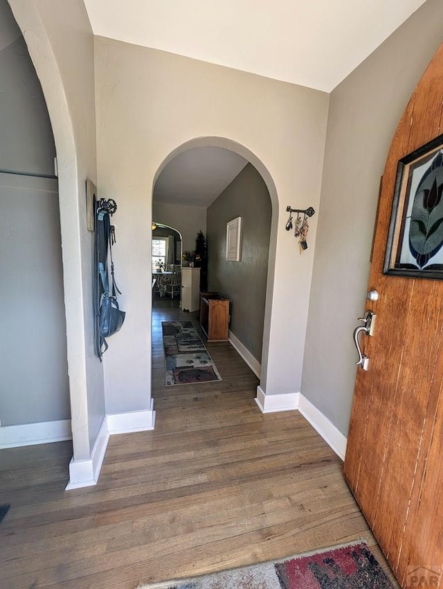 interior space featuring dark wood-style floors, arched walkways, and baseboards