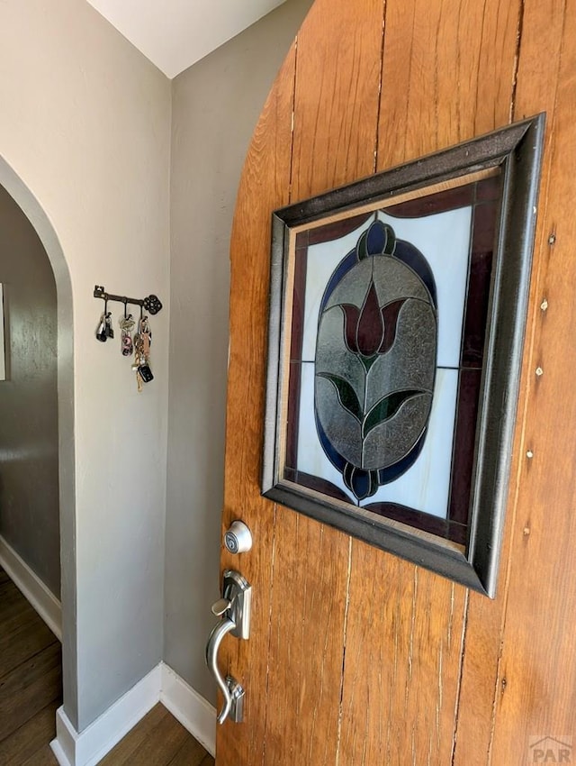 room details featuring baseboards, arched walkways, and wood finished floors