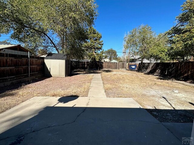 view of yard with an outbuilding, a patio area, a fenced backyard, and a storage shed