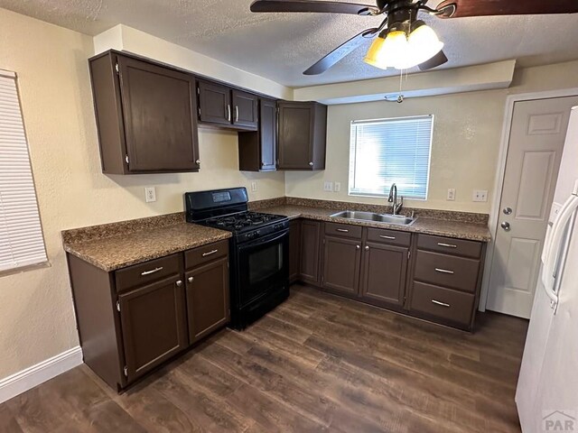 kitchen featuring dark countertops, dark wood-style floors, black range with gas stovetop, and a sink