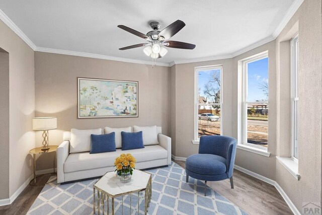 living area featuring baseboards, wood finished floors, and crown molding