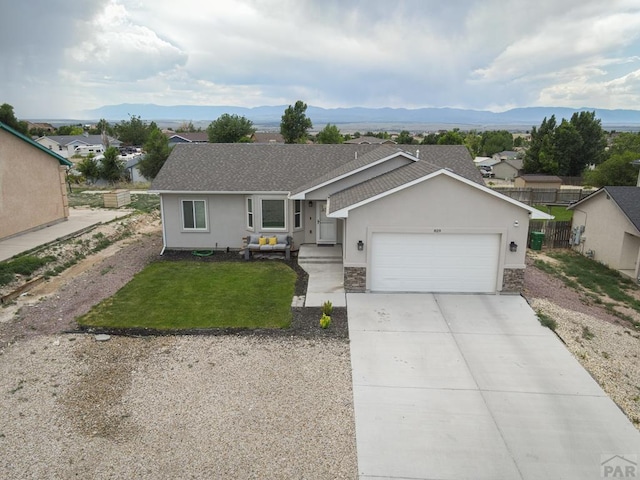 ranch-style house with stucco siding, concrete driveway, an attached garage, a mountain view, and a front lawn