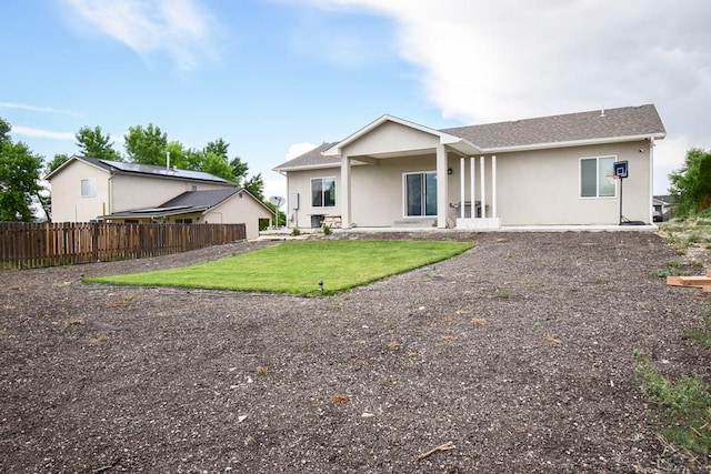 back of house with a yard, fence, and stucco siding