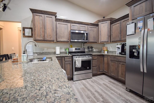 kitchen with appliances with stainless steel finishes, a sink, and light stone countertops